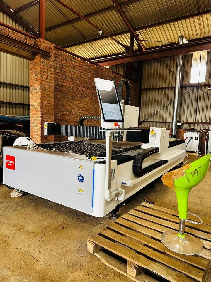 DXTECH fibre laser at Kingson Engineering’s Tynwald workshop, with the cutting bed, cable chain, control screen and extraction duct visible.